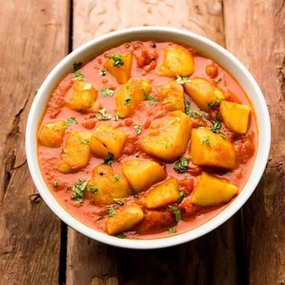 A white bowl filled with Patiala Curry Culture's Indian potato curry, garnished with fresh cilantro.